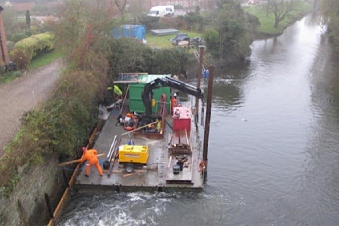 Large raft on the river with people working on it with a crane